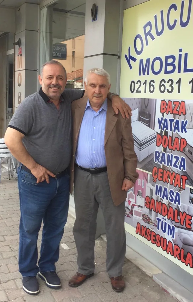 Korucuoğlu Mobilya mağazası önünde yan yana duran iki kişi, aile arşivinden